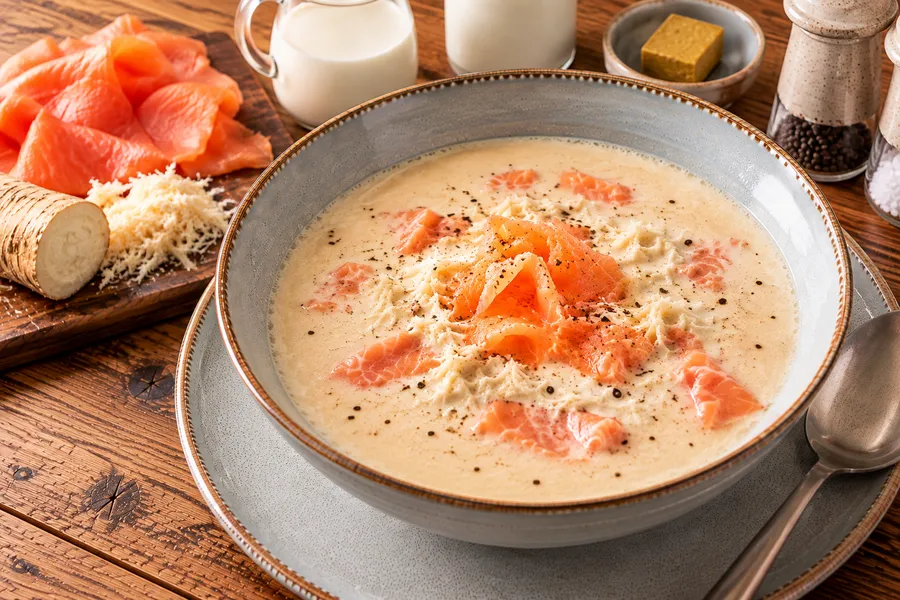 Een opgeschepte portie mierikswortelsoep met gerookte zalm.