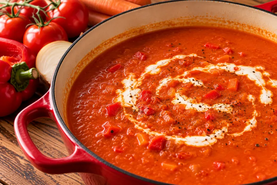 Tomaten-paprikasoep met crème fraîche tijdens het maken, van dichtbij.
